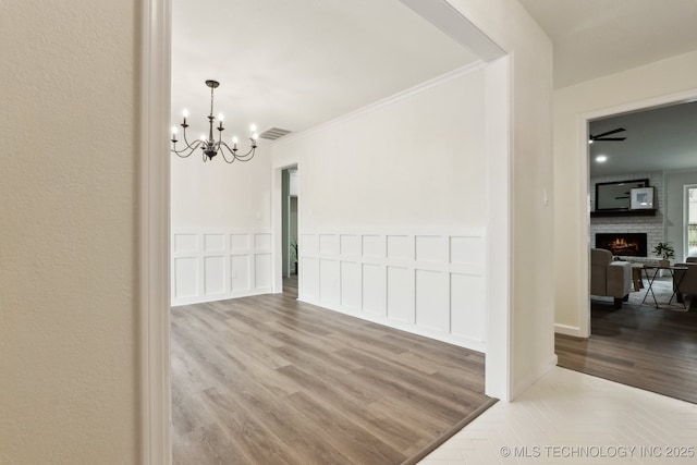 1901 W Indianola St, Broken Arrow, OK 74012 - unfurnished dining area with a chandelier, wood finished floors, a fireplace, a decorative wall, and ornamental molding