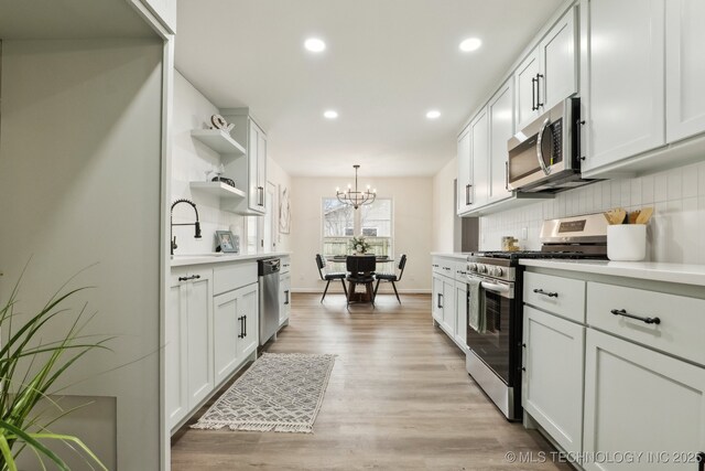 1901 W Indianola St, Broken Arrow, OK 74012 - kitchen with appliances with stainless steel finishes, a sink, open shelves, a chandelier, and backsplash