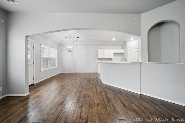 4025 S 217th E Ave, Broken Arrow, OK 74014 - unfurnished living room with dark wood finished floors, a chandelier, baseboards, arched walkways, and recessed lighting