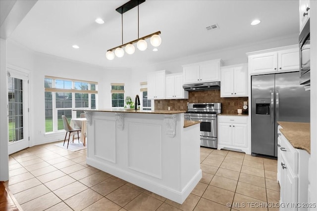 kitchen with appliances with stainless steel finishes, under cabinet range hood, light tile patterned floors, white cabinets, and crown molding