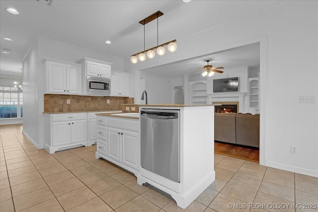 kitchen featuring appliances with stainless steel finishes, light tile patterned floors, a ceiling fan, open floor plan, and tasteful backsplash