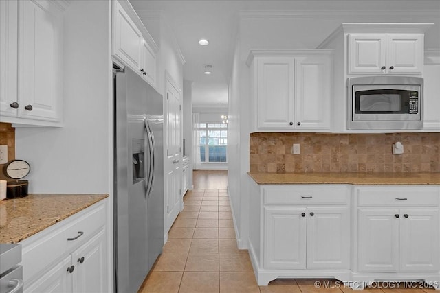 kitchen with stainless steel appliances, white cabinetry, light tile patterned floors, decorative backsplash, and light stone countertops
