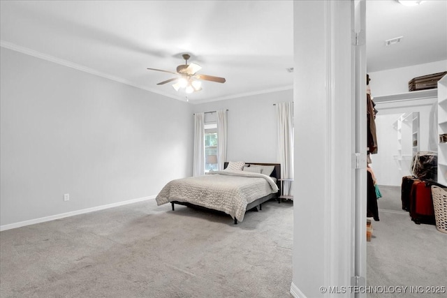 carpeted bedroom with crown molding, a walk in closet, baseboards, and ceiling fan