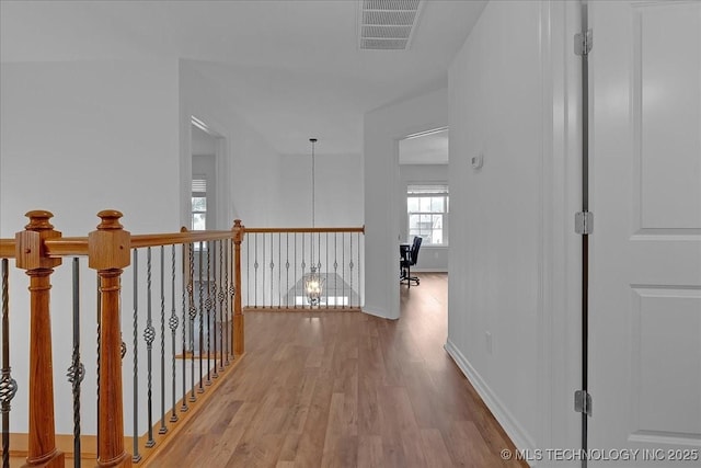 hallway featuring wood finished floors, baseboards, and an upstairs landing