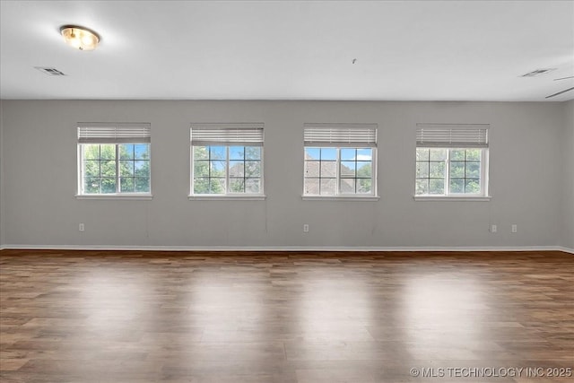 spare room featuring healthy amount of natural light, wood finished floors, and baseboards