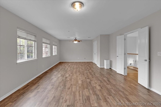 empty room with light wood finished floors, baseboards, and ceiling fan