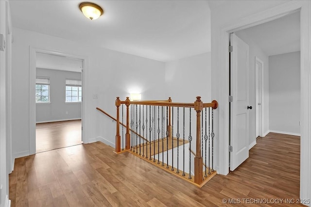 corridor featuring an upstairs landing, wood finished floors, and baseboards