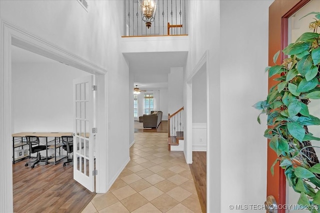 foyer entrance with a towering ceiling, stairway, light tile patterned floors, ceiling fan, and baseboards