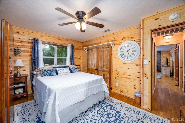 5700 S Wiley Rd, Milburn, OK 73450 - bedroom featuring wooden walls, wood-type flooring, and a ceiling fan