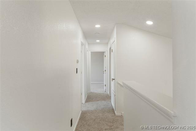 corridor featuring recessed lighting, light carpet, and baseboards