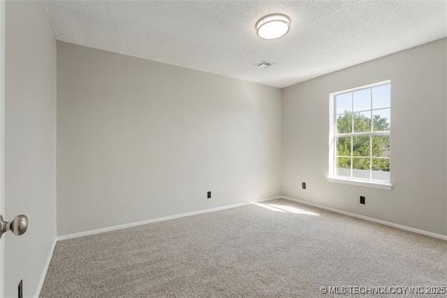 carpeted empty room with a textured ceiling and baseboards