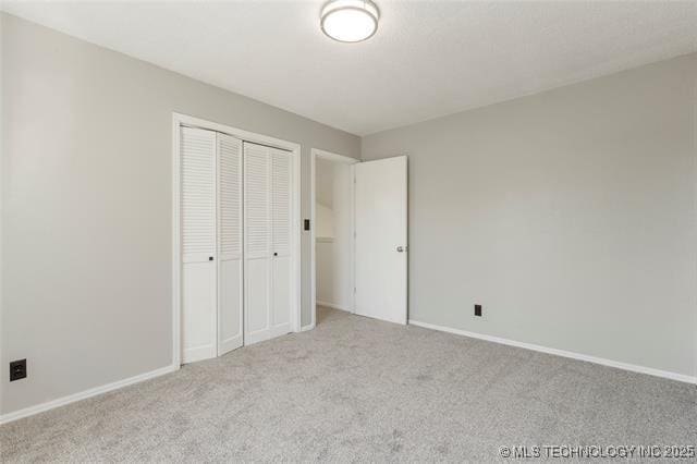 unfurnished bedroom featuring carpet, a closet, and baseboards