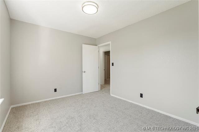 unfurnished room with baseboards and light carpet