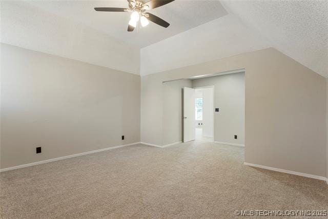 spare room with light carpet, a ceiling fan, lofted ceiling, and baseboards