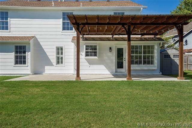 rear view of house with a storage unit, a patio area, an outdoor structure, and a yard