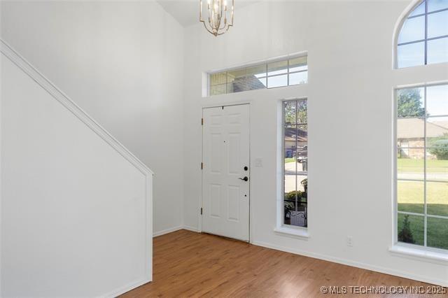 foyer with wood finished floors, a chandelier, plenty of natural light, and a high ceiling