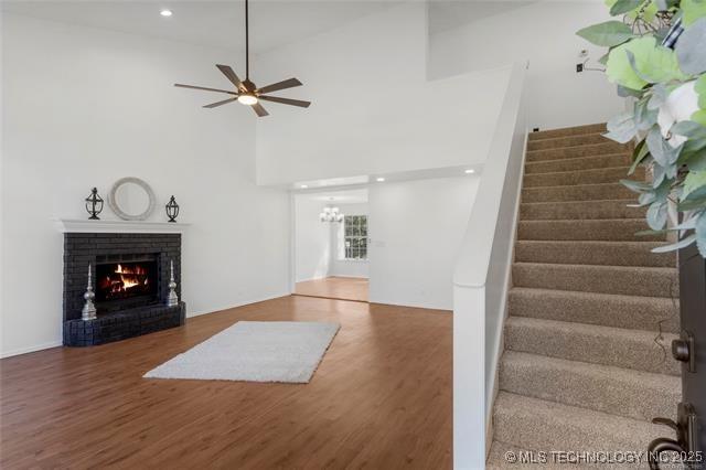 unfurnished living room with stairs, wood finished floors, a fireplace, ceiling fan, and recessed lighting