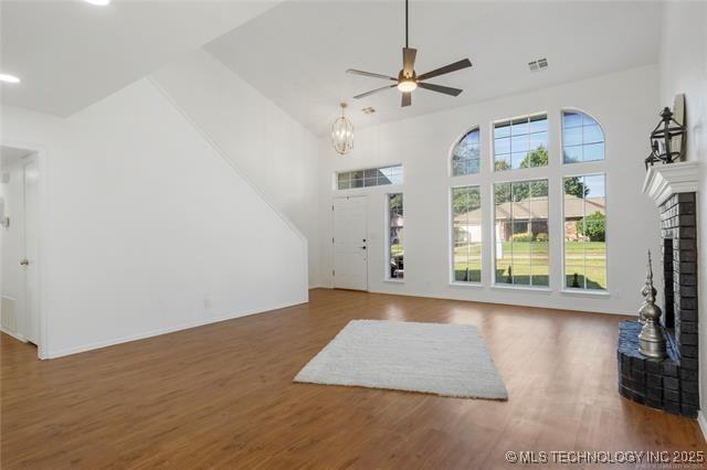 unfurnished living room featuring a fireplace, wood finished floors, a high ceiling, a ceiling fan, and recessed lighting