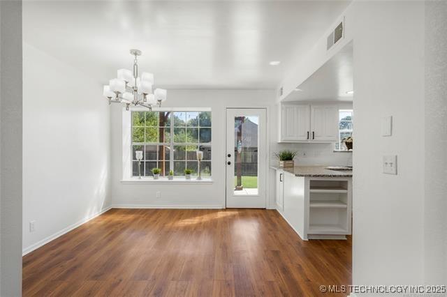 bar with a chandelier, dark wood finished floors, baseboards, and hanging light fixtures