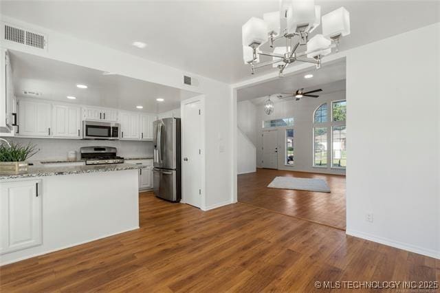 kitchen with stainless steel appliances, white cabinetry, dark wood-type flooring, a chandelier, and recessed lighting