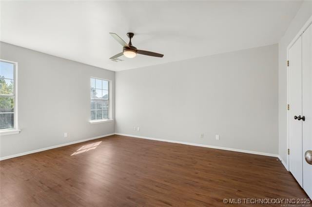 unfurnished bedroom featuring multiple windows, dark wood-style floors, and baseboards