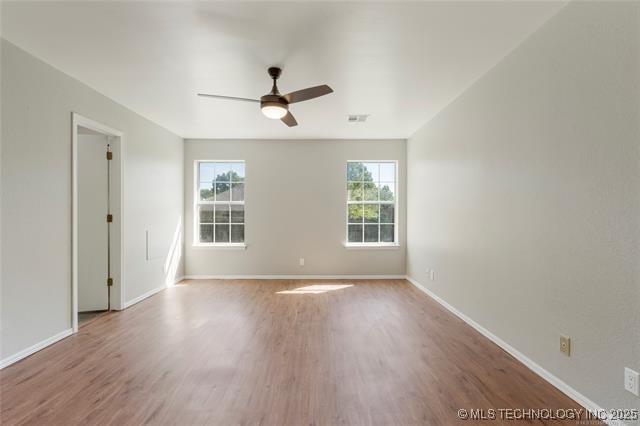 empty room with ceiling fan, wood finished floors, and baseboards
