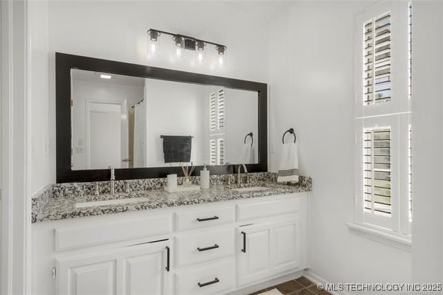 full bathroom with healthy amount of natural light, double vanity, and baseboards