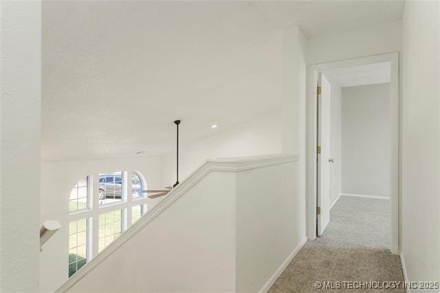 corridor with an upstairs landing, carpet, and baseboards