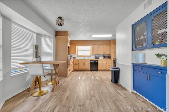 kitchen with appliances with stainless steel finishes, a textured ceiling, light wood-style floors, light brown cabinets, and baseboards