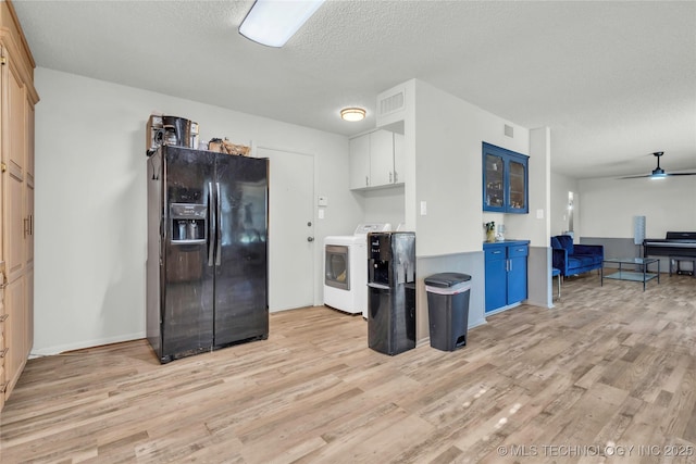 kitchen with black fridge with ice dispenser, independent washer and dryer, light wood finished floors, light countertops, and a textured ceiling