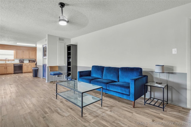 living room with light wood finished floors, a textured ceiling, and ceiling fan