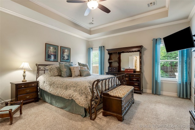 bedroom with a tray ceiling, light colored carpet, crown molding, baseboards, and a ceiling fan