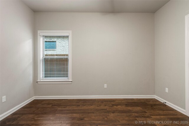 empty room with dark wood-style flooring and baseboards