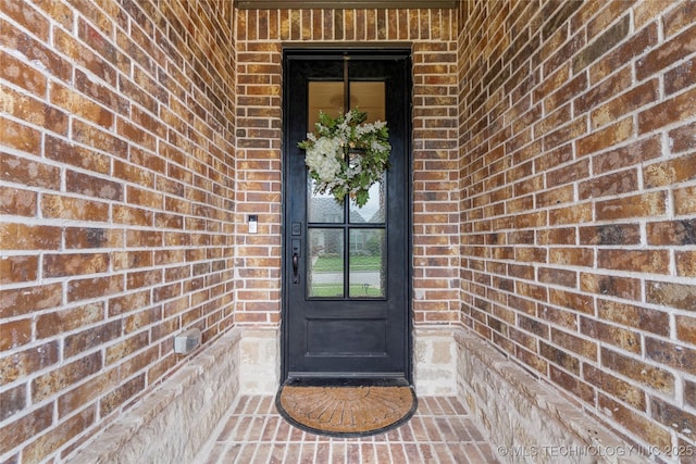 doorway to property featuring brick siding