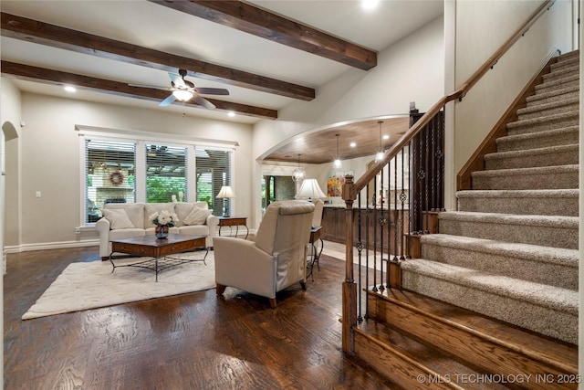 living area featuring arched walkways, a ceiling fan, stairs, beamed ceiling, and recessed lighting
