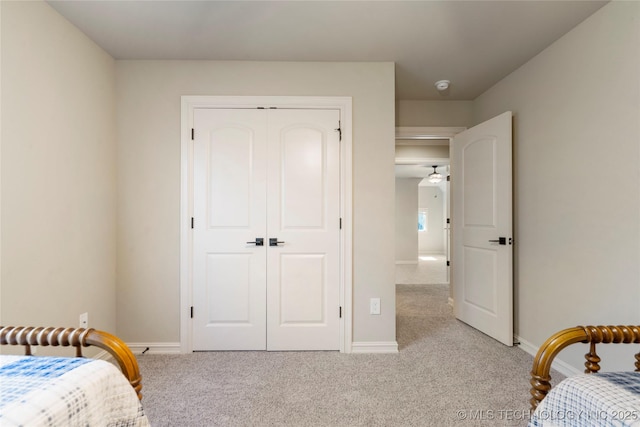 bedroom with light carpet, a closet, and baseboards