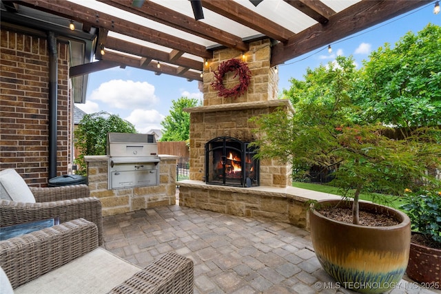 view of patio with an outdoor stone fireplace, exterior kitchen, a pergola, and a grill