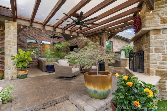 view of patio featuring an outdoor stone fireplace and a ceiling fan