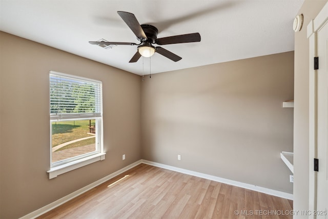 empty room with light wood-style floors, a ceiling fan, baseboards, and a smoke detector
