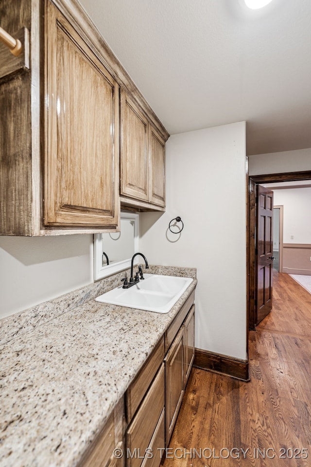 clothes washing area with a sink, dark wood-style flooring, and baseboards