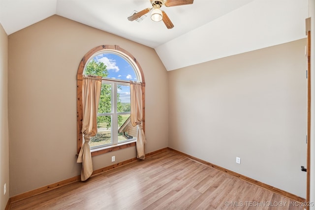 unfurnished room with vaulted ceiling, a ceiling fan, light wood-type flooring, and baseboards
