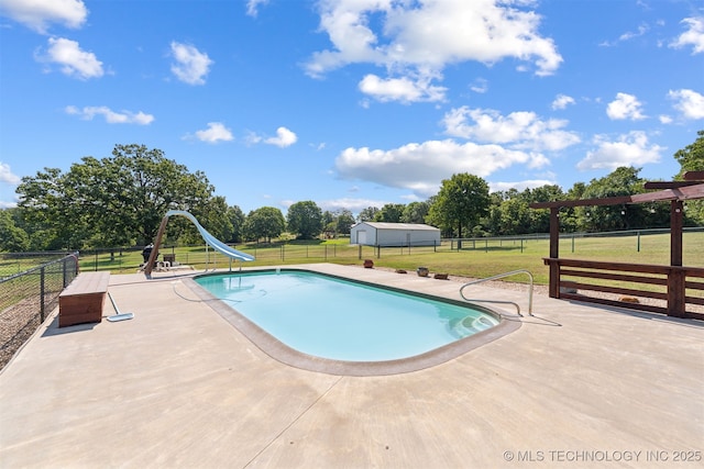 view of swimming pool featuring a water slide, a patio, view of wooded area, and an outdoor structure