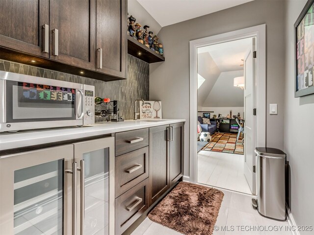 3661 S Lewis Ave, Tulsa, OK 74105 - bar area with wine cooler, stainless steel microwave, light tile patterned floors, backsplash, and vaulted ceiling