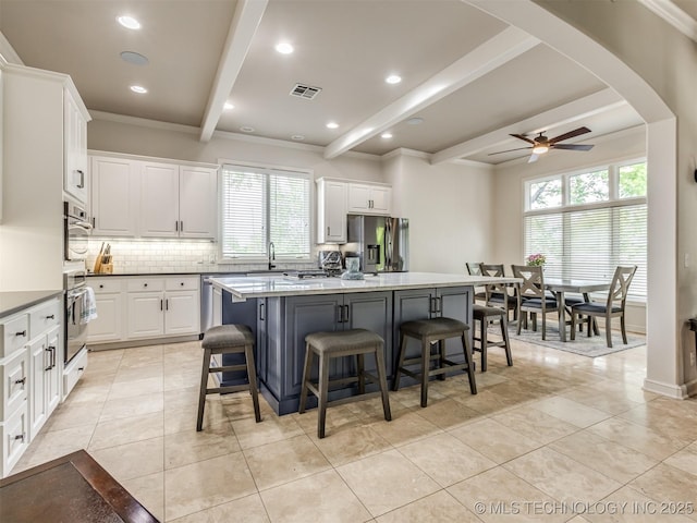 3661 S Lewis Ave, Tulsa, OK 74105 - kitchen featuring stainless steel fridge, beamed ceiling, a kitchen island, white cabinets, and decorative backsplash