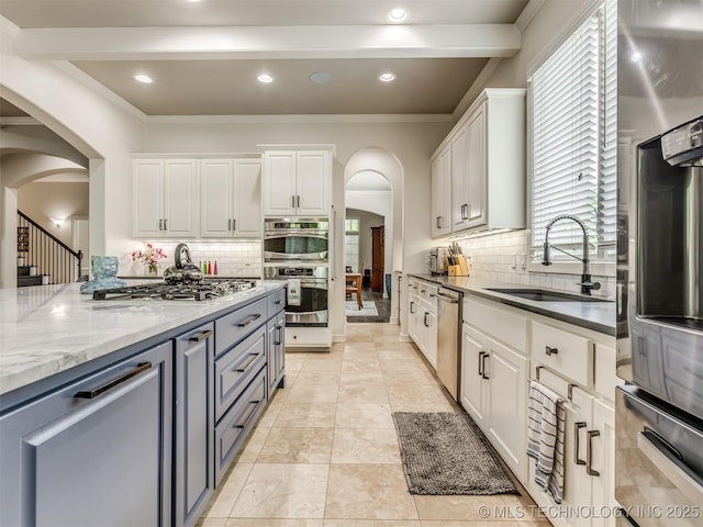 3661 S Lewis Ave, Tulsa, OK 74105 - kitchen featuring stainless steel appliances, arched walkways, white cabinetry, decorative backsplash, and ornamental molding