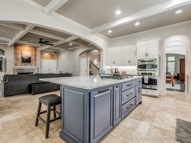 3661 S Lewis Ave, Tulsa, OK 74105 - kitchen featuring white cabinets, ceiling fan, arched walkways, appliances with stainless steel finishes, and backsplash