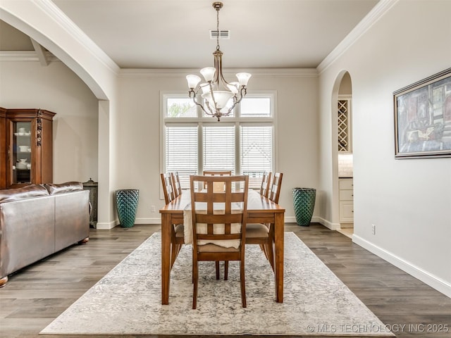 3661 S Lewis Ave, Tulsa, OK 74105 - dining area with arched walkways, a chandelier, wood finished floors, crown molding, and baseboards