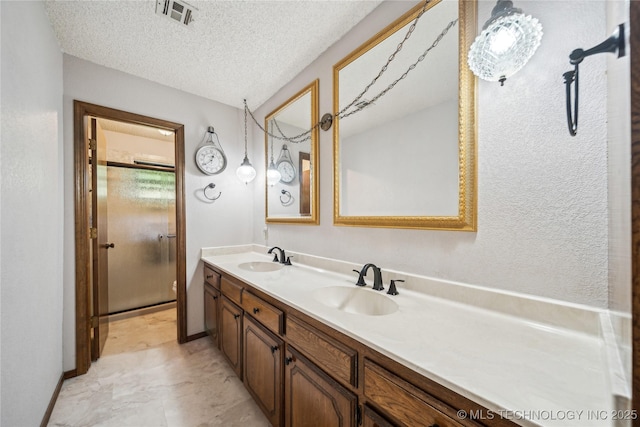 full bath with double vanity, a textured ceiling, and baseboards