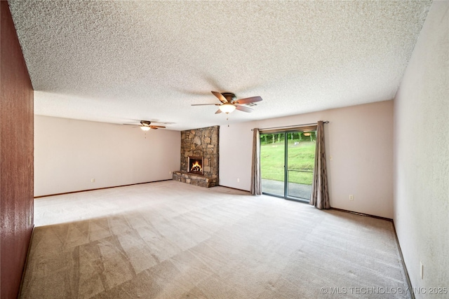 unfurnished living room with a ceiling fan, carpet flooring, a stone fireplace, a textured ceiling, and baseboards