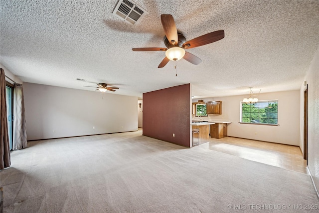 unfurnished living room with a ceiling fan, light colored carpet, a textured ceiling, and a chandelier